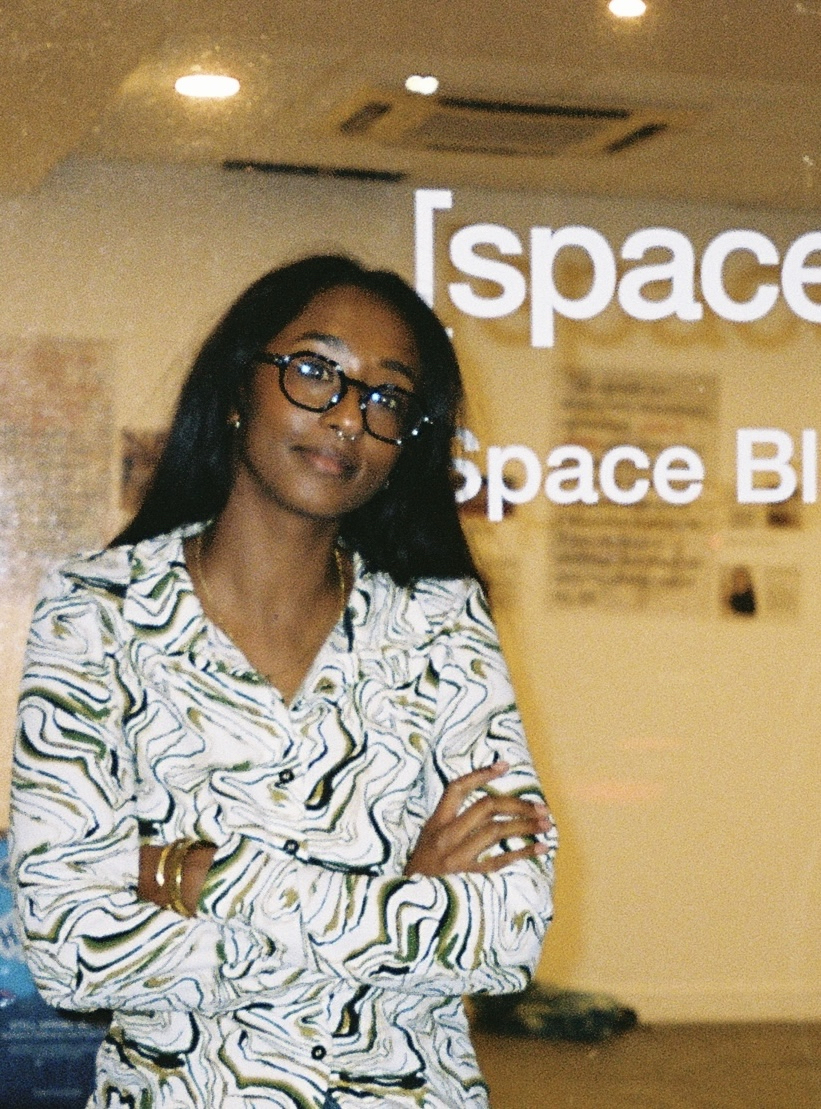 A photo portrait of Tabideee. She stands with her arms crossed, looking into the camera.